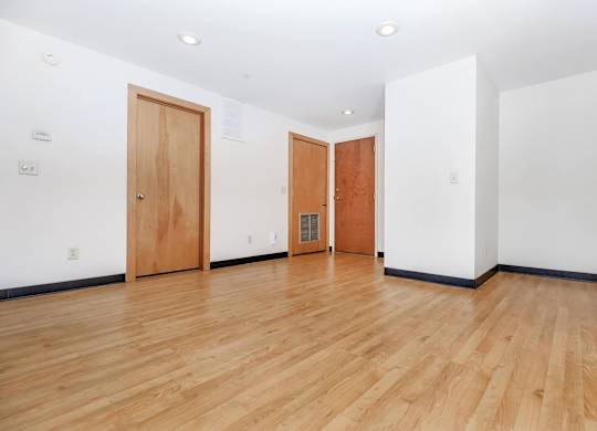 A room with wooden floors and two doors.