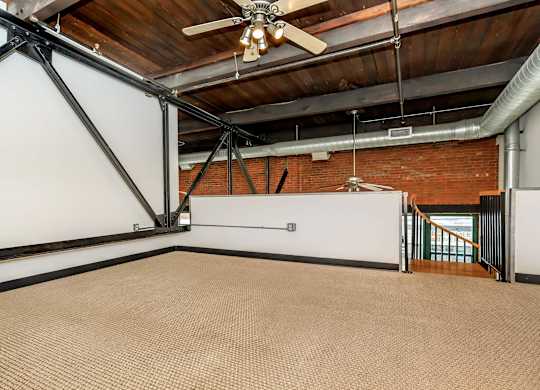A room with a ceiling fan and a brick wall.