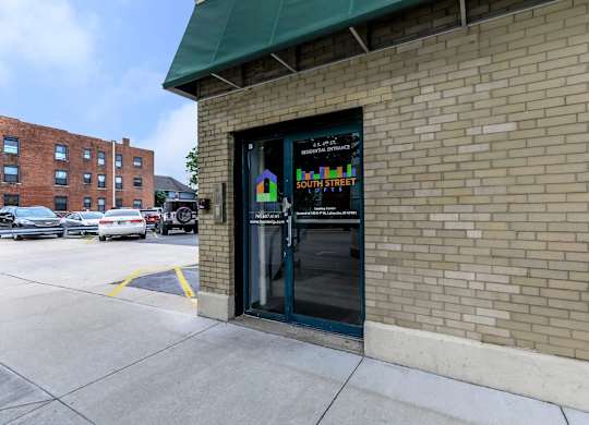 A storefront with a green awning and a glass door with a sign on it.