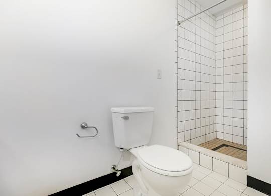A white toilet in a bathroom with a white tiled wall and floor.