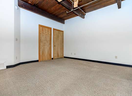A room with a brown carpet and a wooden ceiling.