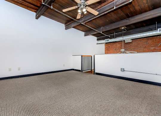 A room with a ceiling fan and a brick wall.
