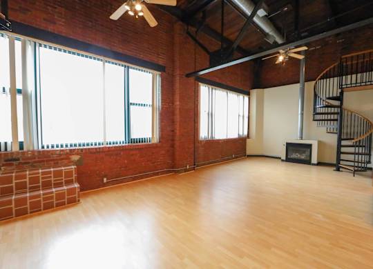 A large empty room with wooden floors and a spiral staircase.
