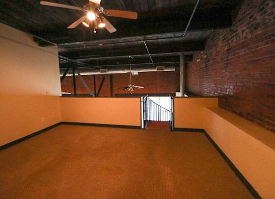 A room with a ceiling fan and a door with a metal railing.
