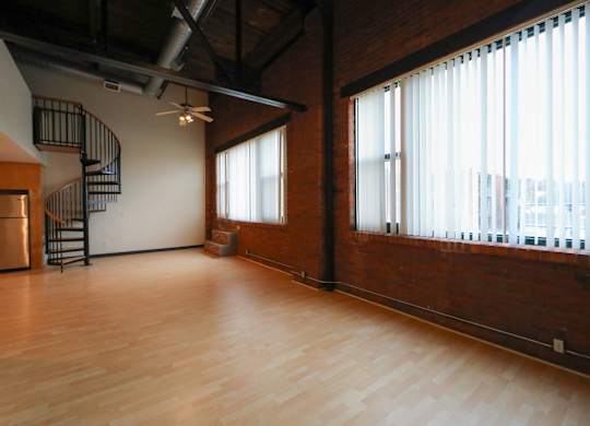 A large empty room with wooden floors and a spiral staircase.