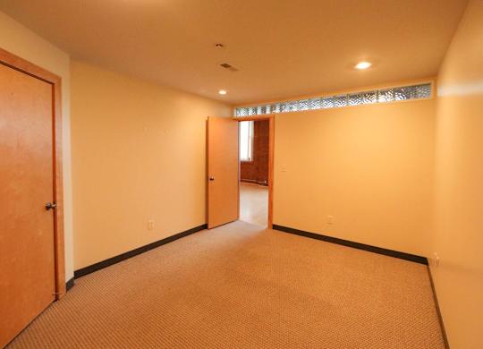 A room with a carpeted floor and a door on the left.