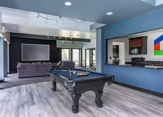A pool table is in the middle of a room with a couch and a television.