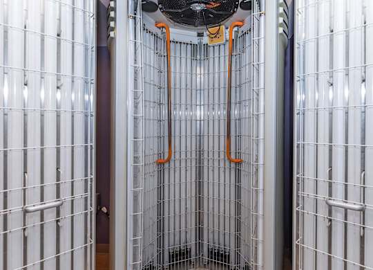 A wall of white panels with orange pipes hanging from the ceiling.