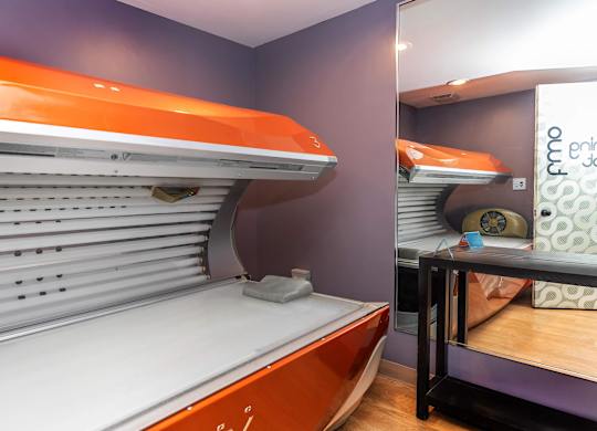 A bed with orange headboard and footboard in a room.