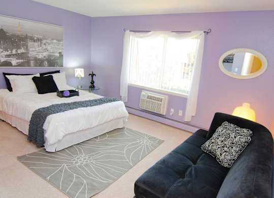 A bedroom with a bed, a couch, and a window.