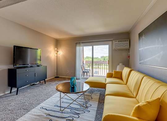 A living room with a yellow couch and a television.