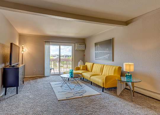 A living room with a yellow sofa and a glass coffee table.