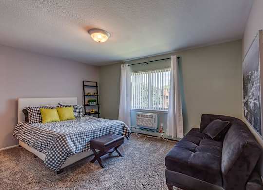 A bedroom with a bed, chair, and window.