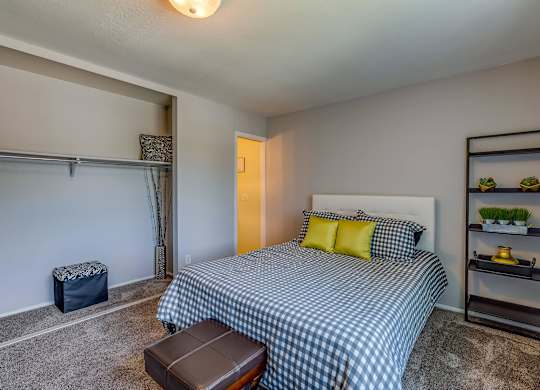 A bedroom with a bed, a bench, and a shelf with plants.