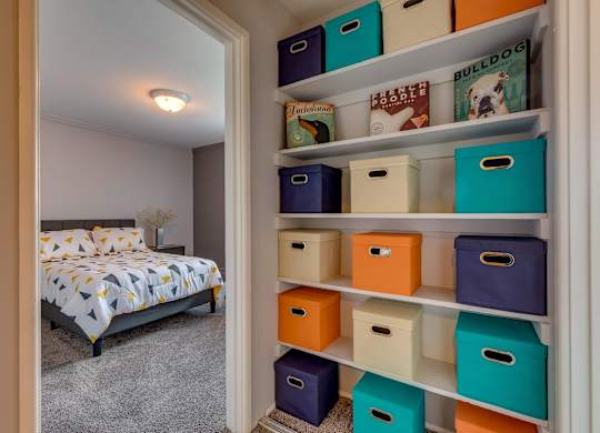 A bedroom with a bed and a shelf with storage boxes.