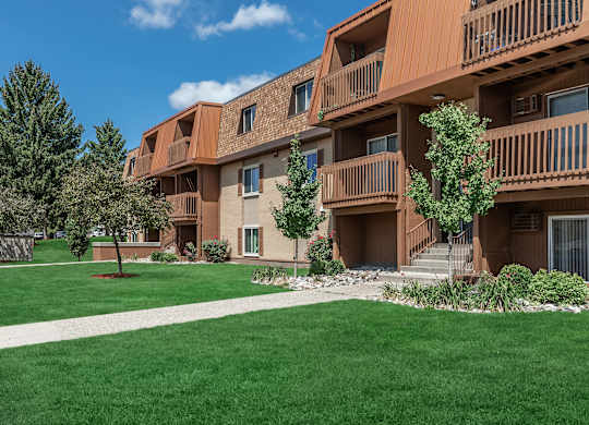 Apartment complex with brown buildings and green lawns.