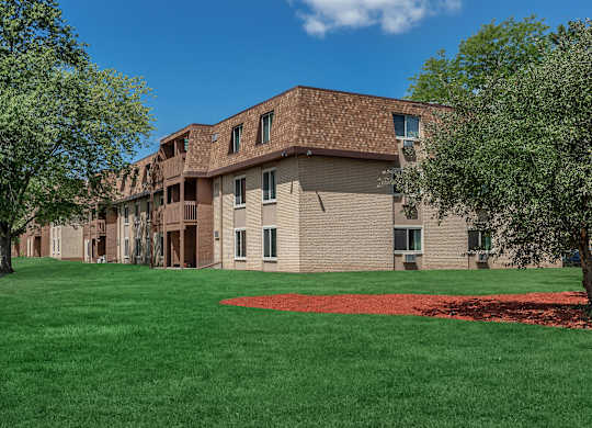 A large building with a red roof and a green lawn in front.