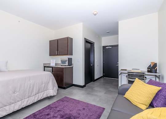 A bedroom with a bed, a couch, and a cabinet.