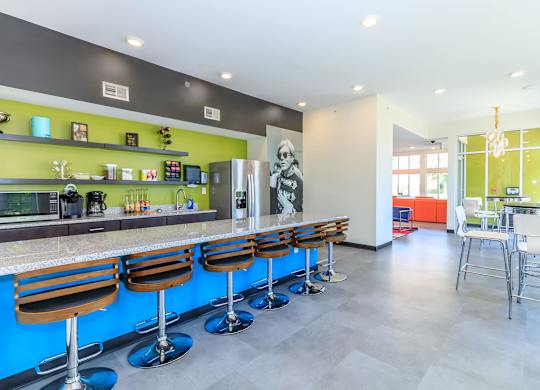 A modern bar with blue stools and a green wall.