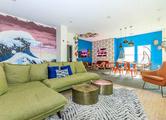 A living room with a large green sofa and a painting of a mountain scene on the wall.