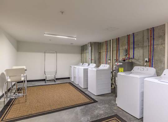 A laundry room with a washer and dryer on the right and a chair on the left.