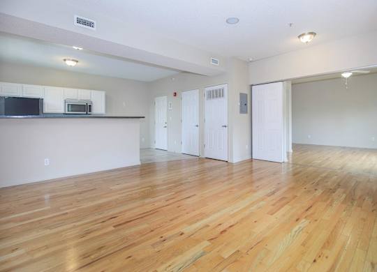 A spacious room with wooden flooring and white walls.
