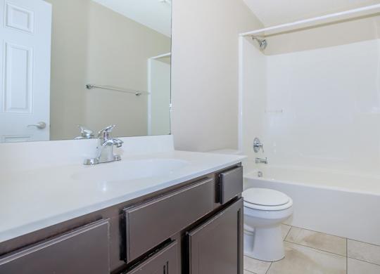 A white sink with a silver faucet and a white toilet in a bathroom.