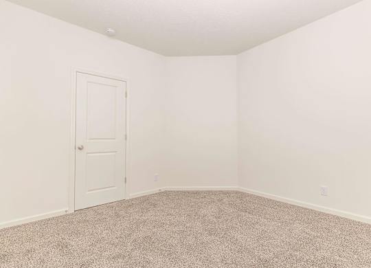 A room with a carpeted floor and a white door.