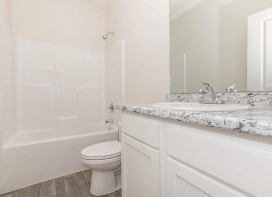 A white toilet sits in a bathroom next to a marble counter.