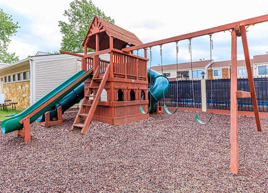 A playground with a green slide and a red wooden structure.