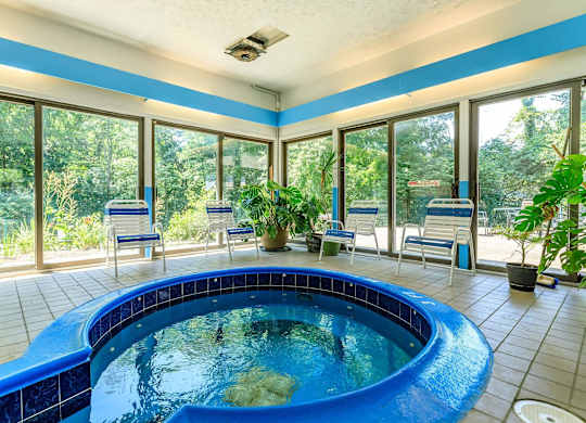 A round blue pool in a room with tiled floors and ceilings.