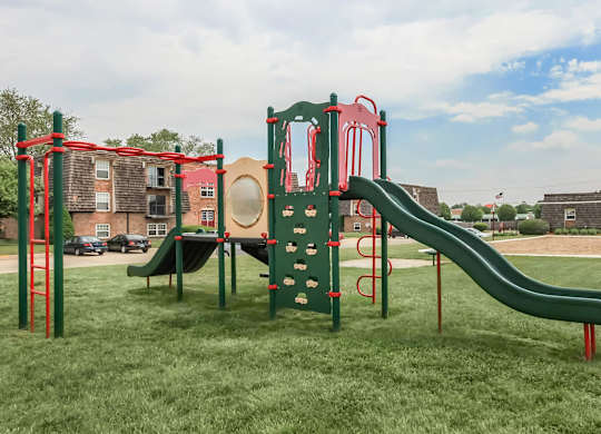 A playground with a green slide and red and green play structure.