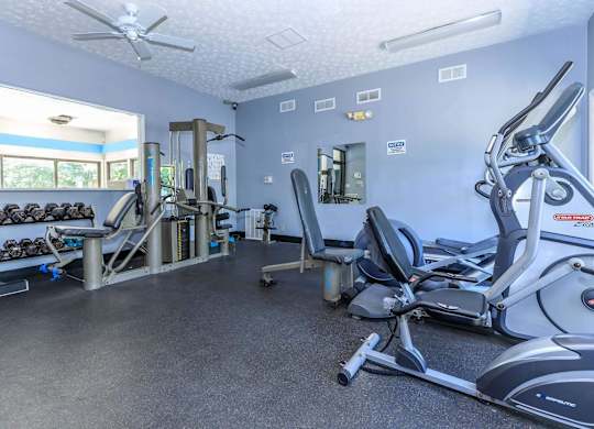 A gym with a variety of equipment including treadmills, weights, and exercise machines.