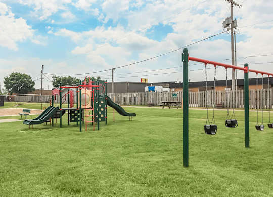 A playground with a red swing set and a green slide.