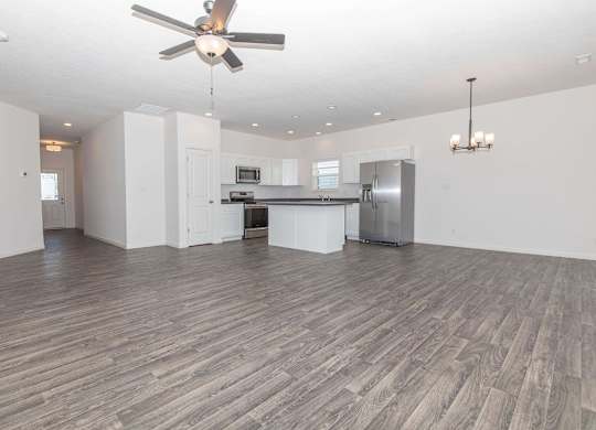 A spacious room with a ceiling fan and wooden flooring.