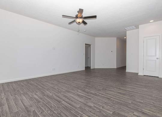 A room with a ceiling fan and wood flooring.