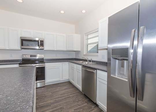 A kitchen with a stainless steel refrigerator and white cabinets.