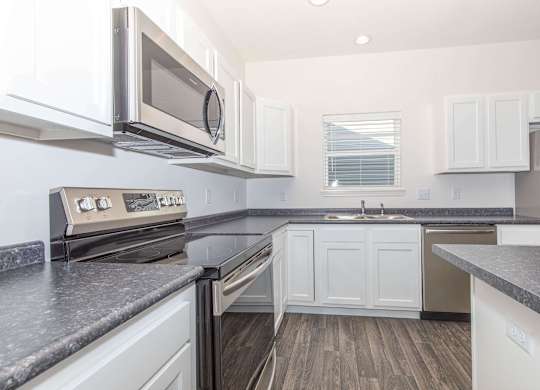 A modern kitchen with white cabinets and a black countertop.