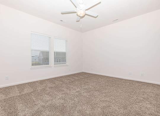 A room with a ceiling fan and carpeted floor.
