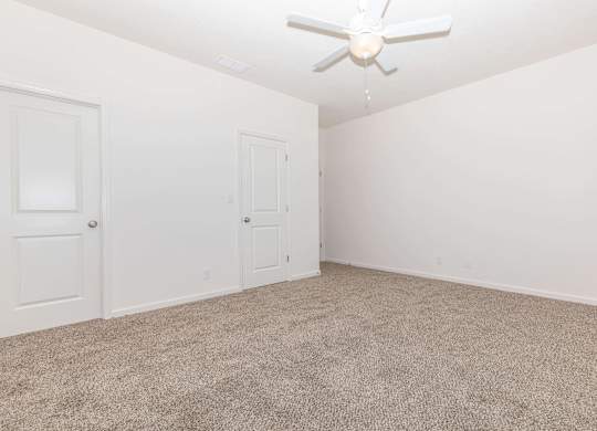 A room with a ceiling fan and carpeted floor.