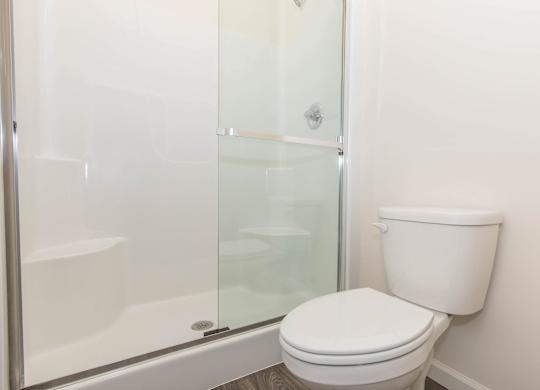 A white toilet sits next to a glass shower stall.
