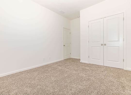 A room with carpeted floor and two doors.
