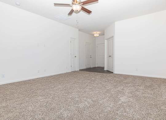 A room with a ceiling fan and carpeted floor.