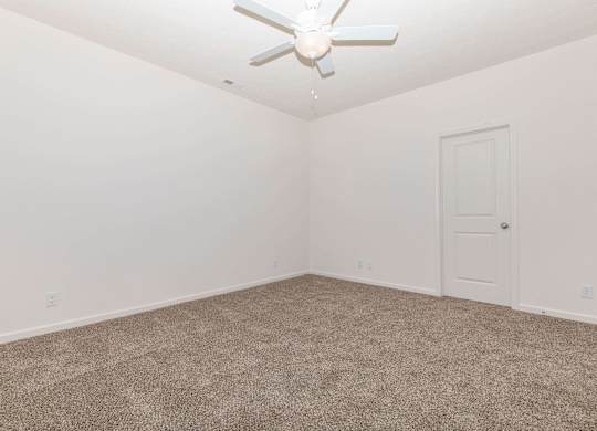 A room with a ceiling fan and carpeted floor.