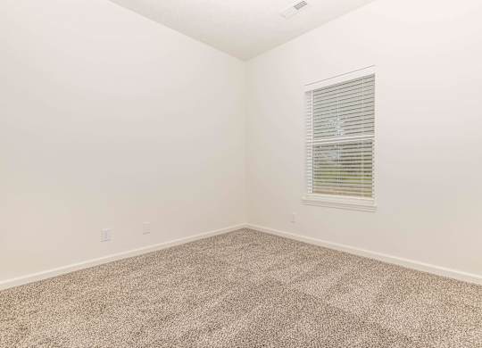 A room with a carpeted floor and a window with blinds.
