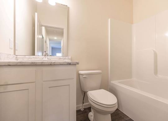 A white toilet sits next to a white bathtub in a bathroom.