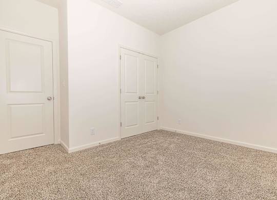 A room with two doors and carpeted floor.