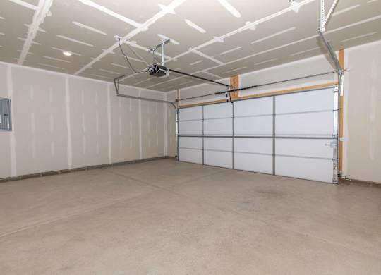 A spacious garage with a white ceiling and a white garage door.