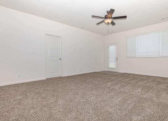 A room with a ceiling fan and carpeted floor.
