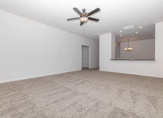 A room with a ceiling fan and carpeted floor.